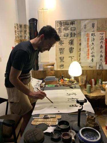 a man is working on a piece of paper at Zhangjiajie One Art Guesthouse in Zhangjiajie