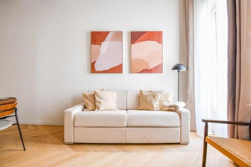 un canapé blanc dans un salon avec des œuvres d'art sur le mur dans l'établissement Le Paul - Appart de standing avec 2 ch et clim, à Marseille