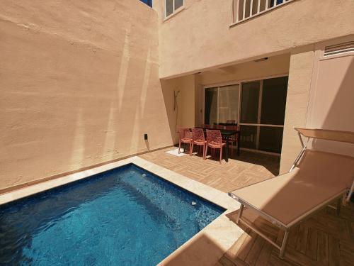 uma piscina ao lado de um edifício com uma mesa e cadeiras em Ramla Valley Vista in Nadur Gozo em Nadur