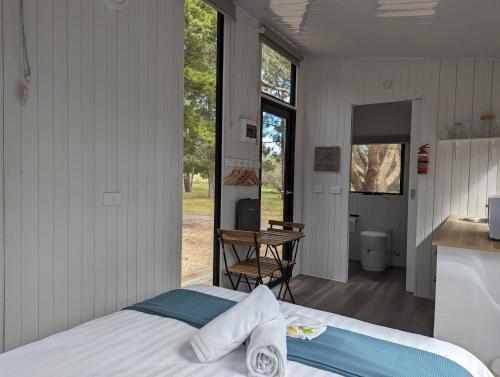 ein Schlafzimmer mit einem Bett und eine Küche mit einem Tisch in der Unterkunft Tiny House 16A at Grampians Edge in Dadswells Bridge