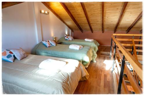 three beds in a room with wooden ceilings at Ocho Cabañas in San Carlos de Bariloche