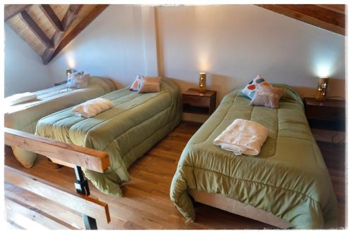 two beds in a room with wooden floors at Ocho Cabañas in San Carlos de Bariloche