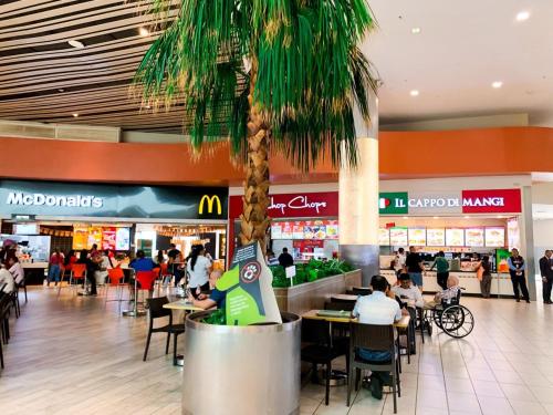 a palm tree in a mall with people sitting at tables at Airbnb Guayaquil, Mall del Sol, Piso alto in Guayaquil