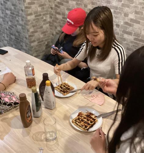 a group of people sitting around a table eating food at Osaka Namba Hostel MIYABI in Osaka