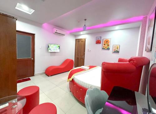 Habitación con cama y sillas rojas. en Amura Hotel Quận 7, en Ho Chi Minh