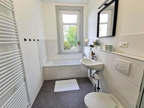 La salle de bains blanche est pourvue d'un lavabo et de toilettes. dans l'établissement BohnApartments - Stadtblick Zechenhaus - Balkon - gratis Parkplatz - WLAN - sehr ruhig - barrierearm, à Ilmenau