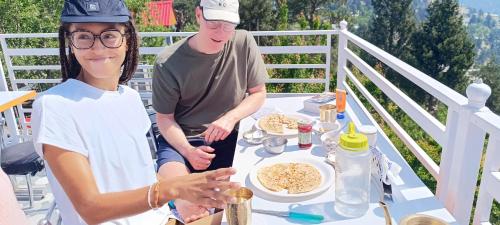a man and woman sitting at a table with food at Kin Vatika Homestay in Kalpa