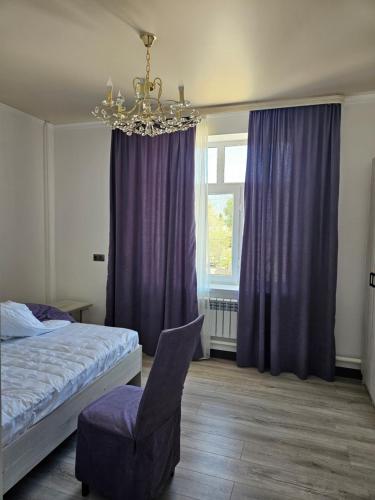a bedroom with a bed and a chair and a chandelier at Seitek Hotel in Kochkor