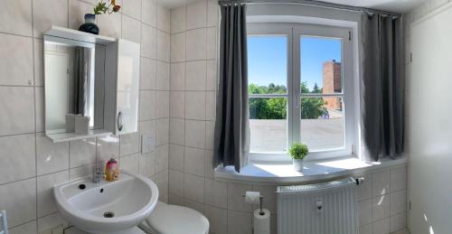 a bathroom with a sink and a toilet and a window at Ferienwohnung Nikolaiblick in Jüterbog