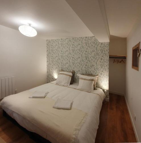 a bedroom with a large bed with white sheets and pillows at Les appartements de Clélia in Ax-les-Thermes