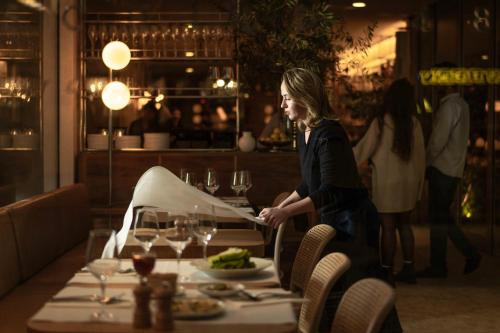 a woman standing at a table in a restaurant at R48 Hotel and Garden in Tel Aviv