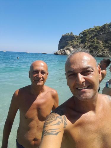 two men standing in the water at the beach at DE MEO Guest House in Castellammare del Golfo