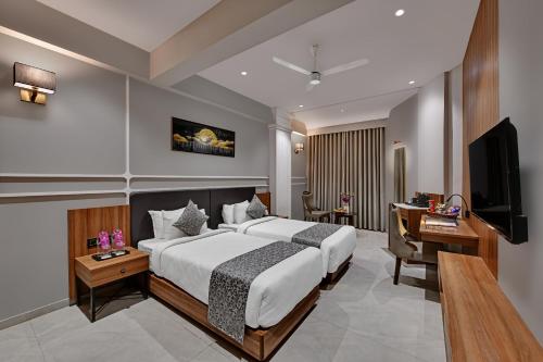 a bedroom with a bed and a desk and a television at Regenta Inn Motikhavdi Jamnagar in Jamnagar