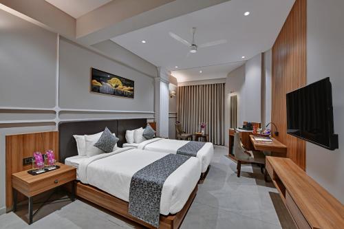 a bedroom with a bed and a desk and a television at Regenta Inn Motikhavdi Jamnagar in Jamnagar