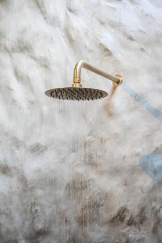 a shower with water coming out of it at Ria Uluwatu, Tropical Chic Hotel in Uluwatu