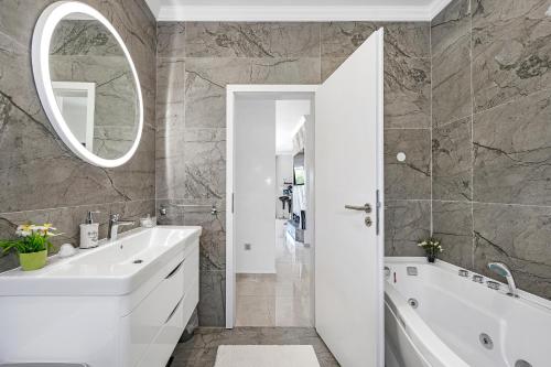 a bathroom with a tub and a sink and a mirror at Villa VERONICA with CINEMA PROJECTOR by the HEATED POOL and JACUZZI in Šibenik