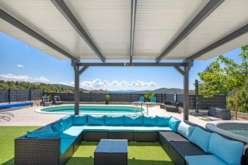 a patio with a blue couch and a pool at Villa VERONICA with CINEMA PROJECTOR by the HEATED POOL and JACUZZI in Šibenik