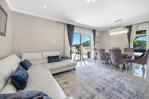 a living room with a white couch and a table at Villa VERONICA with CINEMA PROJECTOR by the HEATED POOL and JACUZZI in Šibenik