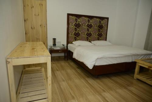 a bedroom with a bed and a wooden table at Saadhan Homestay in Mussoorie