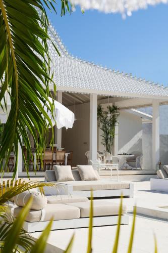 a patio with white couches and a table and chairs at Ria Uluwatu, Tropical Chic Hotel in Uluwatu