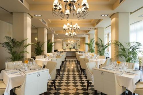 een restaurant met witte tafels en stoelen en een kroonluchter bij Haven Boutique Hotel in Durban