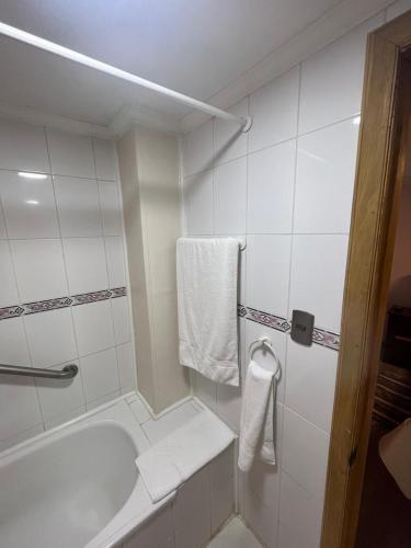 a bathroom with a tub and a shower with towels at Hostal Español Coyhaique in Coihaique