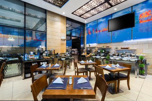 un restaurante con mesas y sillas de madera y TV en Sulaf Luxury Hotel, en Amán