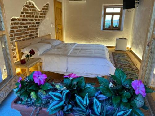 a bedroom with a bed and some purple flowers at Guesthouse Vitoria - Mrizi i Zanave in Fishtë