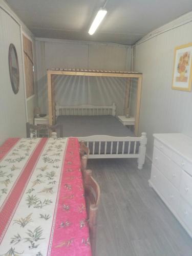 une petite chambre avec deux lits et un pare-lit dans l'établissement Camping à la ferme de la tournerie, à Raids