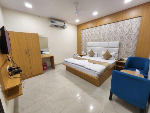 um quarto com uma cama, uma televisão e uma cadeira em Hotel Mandakini Royale Near PVR Deep Cinema Hall Kanpur em Kānpur