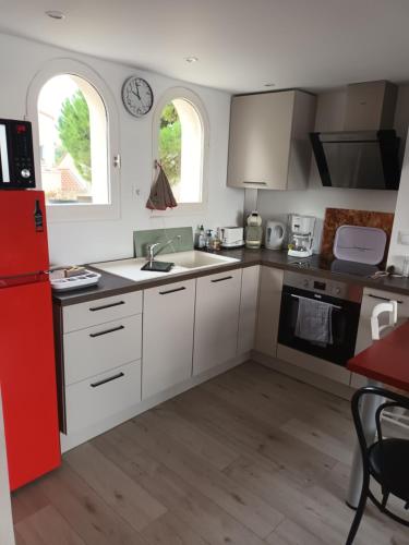 La cuisine est équipée de placards blancs et d'un réfrigérateur rouge. dans l'établissement appt avec magnifique vue sur le port, à Meschers-sur-Gironde