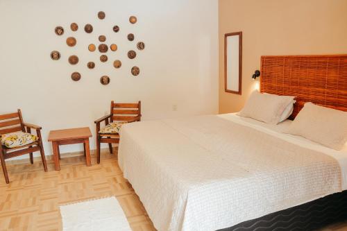 a bedroom with a bed and two chairs and a clock on the wall at Ajubá Pousada in Morro de São Paulo