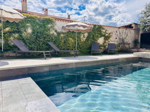 une piscine avec deux chaises et un parasol dans l'établissement Villa Lou Carou - Vue mer et Baie de Nice, à Cagnes-sur-Mer