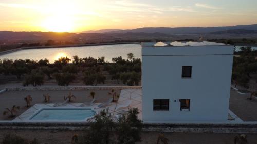 un edificio con piscina frente a la puesta de sol en Casita del embalse con encanto en Biar