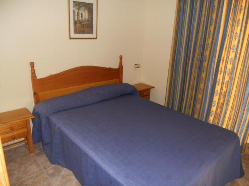 a bedroom with a bed with a blue comforter at Apartamentos Palas Salou in Salou