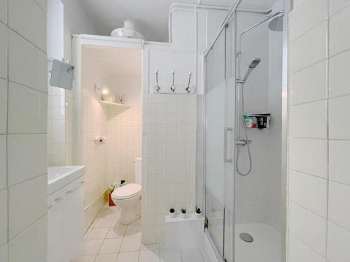 La salle de bains blanche est pourvue d'une douche et de toilettes. dans l'établissement Le parc de l'Hermitage, à Le Touquet-Paris-Plage