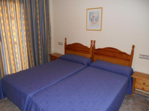 1 Schlafzimmer mit 2 Betten und blauer Bettwäsche in der Unterkunft Apartamentos Palas Salou in Salou