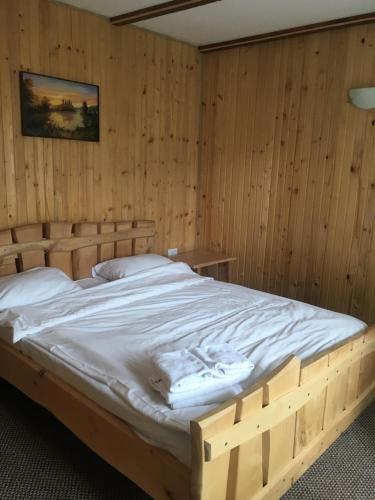 a large bed in a room with wooden walls at Guest house Zatishniy dvir in Yaremche