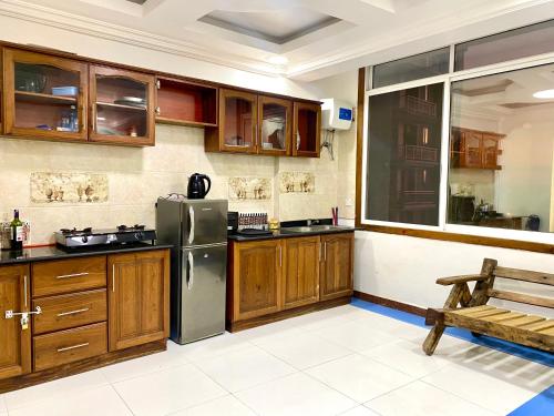 a kitchen with wooden cabinets and a stainless steel refrigerator at Amazing Apartment Free Parking & Security in Dar es Salaam