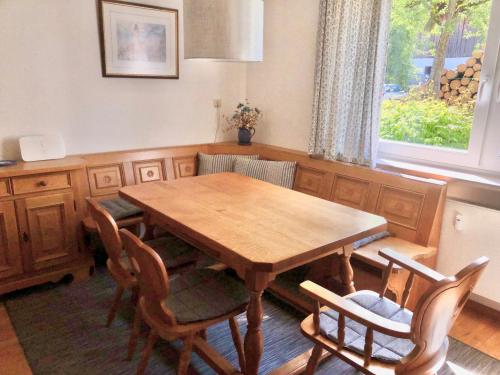 uma mesa de jantar em madeira com cadeiras e uma janela em Ferienwohnung Gartenblick em Amerang