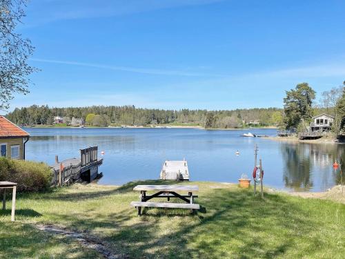 a picnic table next to a lake with a dock at 4 star holiday home in LJUSTERÖ in Norra Ljustero