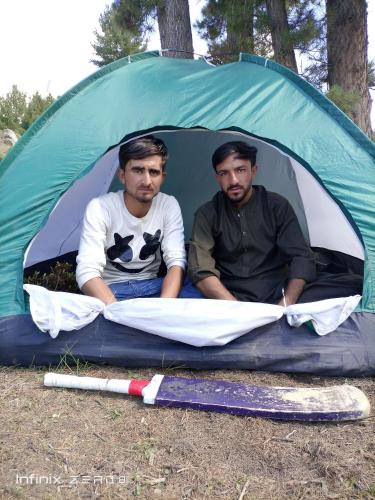 zwei Männer sitzen in einem grünen Zelt in der Unterkunft Bojol Guesthouse bilamike thoursay in Skardu
