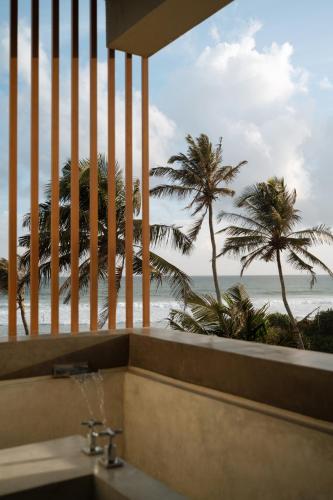 a bathroom with a view of the ocean and palm trees at Harding Boutique Hotel in Ahangama