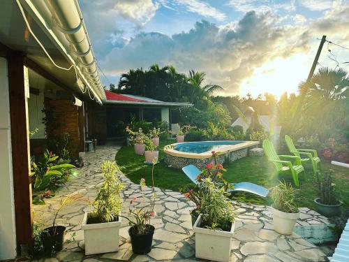 een achtertuin met een zwembad en planten en stoelen bij Bellevue Raiatea in Uturoa