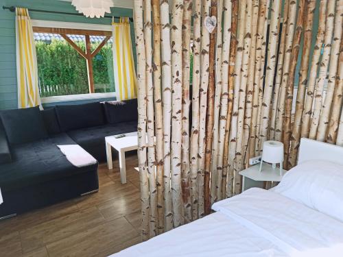a room with a bed and a living room with a couch at Pod Wierzbami in Żuławki