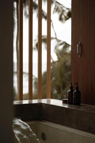 a window with two bottles sitting on a ledge at Harding Boutique Hotel in Ahangama