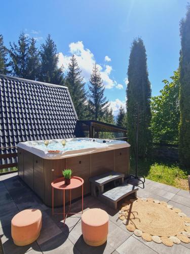 - un bain à remous sur une terrasse avec une table et des tabourets dans l'établissement Cabane A-frame CeziAde Tihuta, à Piatra Fântânele