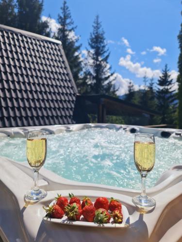 two glasses of champagne and strawberries in a swimming pool at Cabane A-frame CeziAde Tihuta in Piatra Fantanele