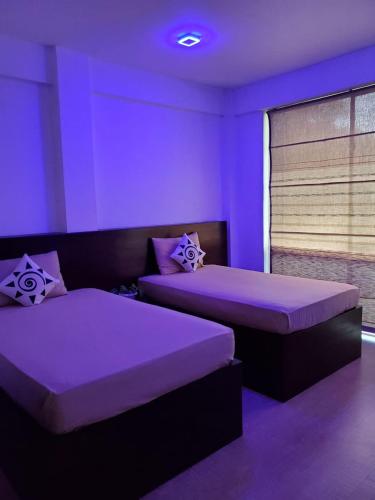 a purple room with two beds and a window at Royal Restaurant in Warakapola
