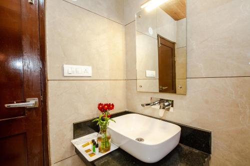 a bathroom with a sink and a vase of flowers at Tripli Hotels Drilbu Manali in Manāli